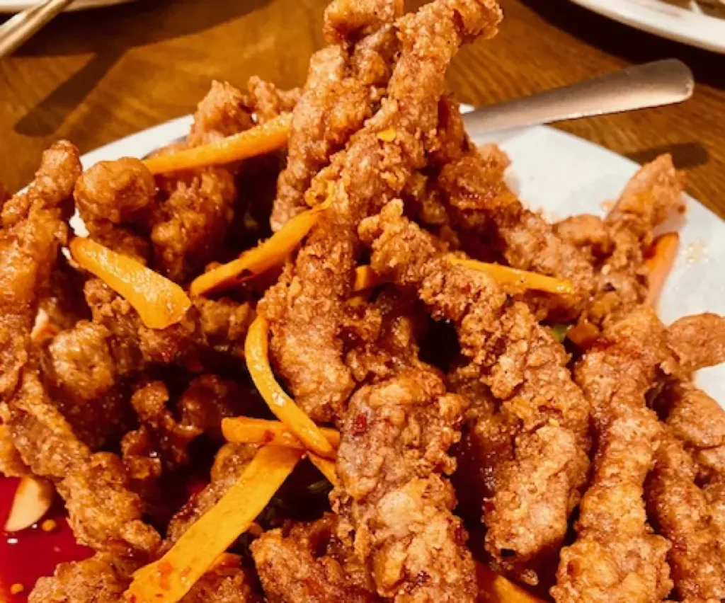 Deep fried ginger beef on a white plate