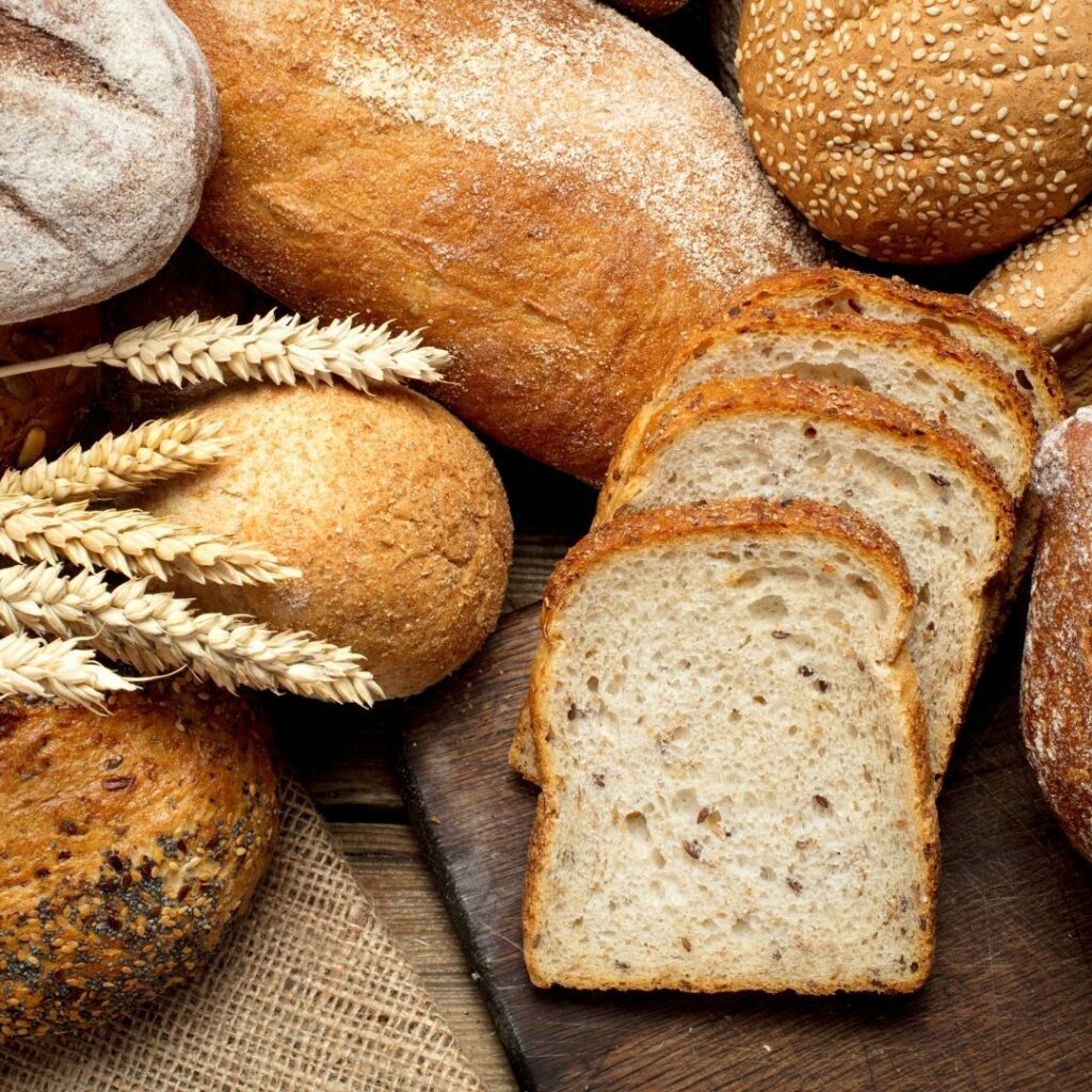 A close up photo of loaves and sliced bread on a wooden background.