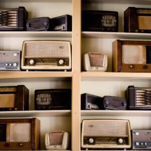 Four shelves with antique radios on them